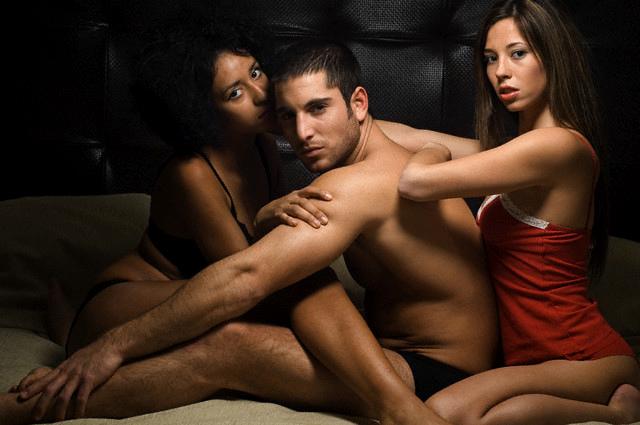 man in bed with two women