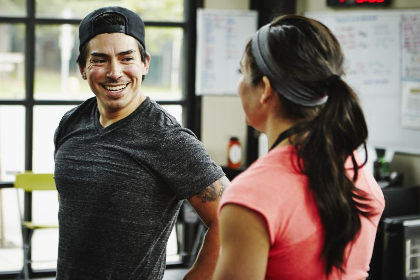 man making small talk to a woman in the gym